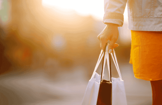 Persona saliendo de compras con bolsas, gracias a un préstamo rápido y seguro en Turbocredito.mx